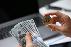 Une personne tient un bitcoin dans une main et des dollars dans l'autre